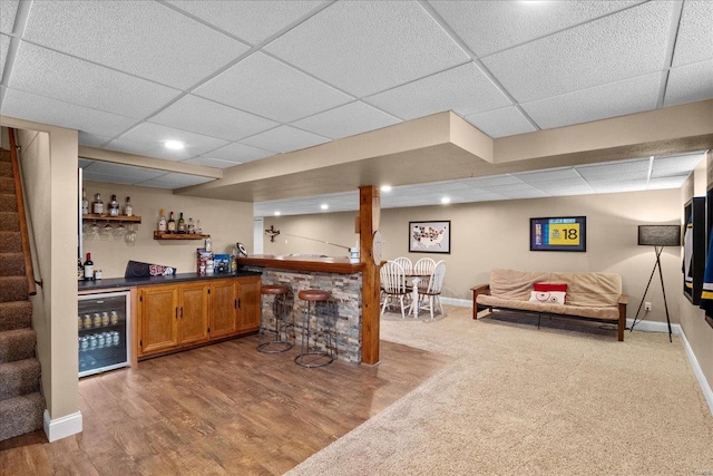 bar featuring wine cooler, a paneled ceiling, and wood-type flooring