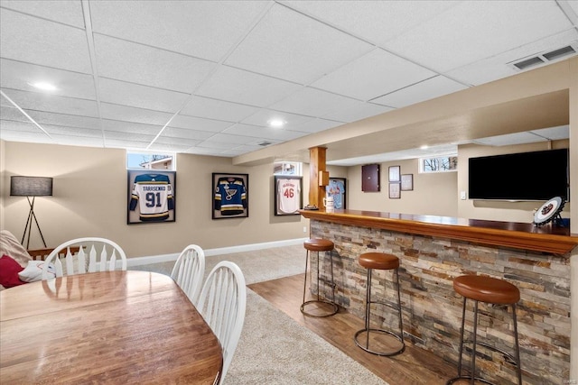 bar with hardwood / wood-style floors and a drop ceiling