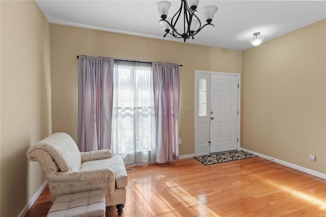 entrance foyer with a notable chandelier, light wood-style flooring, baseboards, and a wealth of natural light