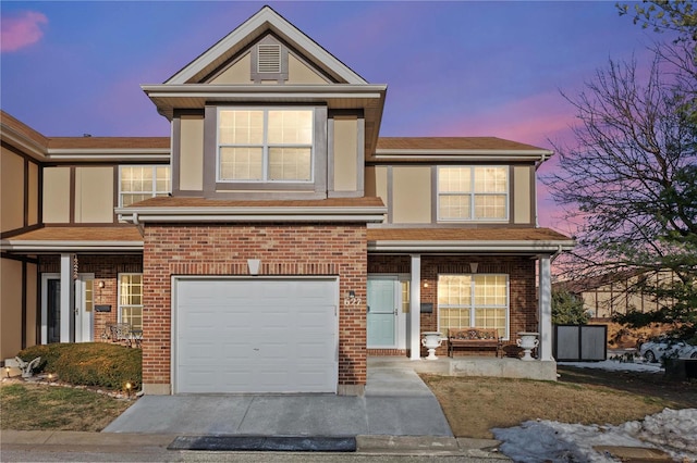 traditional-style house with an attached garage, stucco siding, driveway, and brick siding