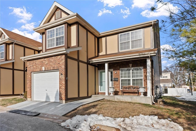 english style home with a garage, brick siding, driveway, and stucco siding