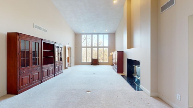 living room with a fireplace, light colored carpet, and a high ceiling