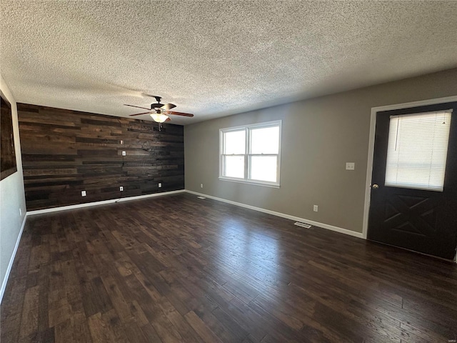 interior space featuring ceiling fan, dark hardwood / wood-style floors, a textured ceiling, and wood walls