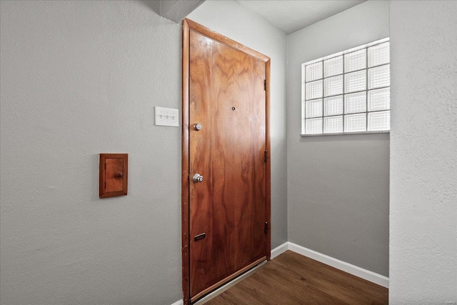 entryway with dark wood-style flooring and baseboards