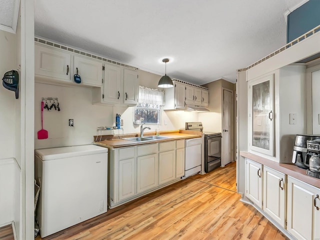 kitchen with stainless steel electric stove, decorative light fixtures, sink, fridge, and light hardwood / wood-style floors