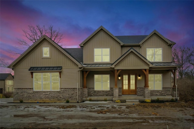 craftsman inspired home featuring a standing seam roof, brick siding, metal roof, and covered porch