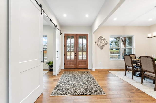 entrance foyer with light wood-type flooring, baseboards, plenty of natural light, and a barn door