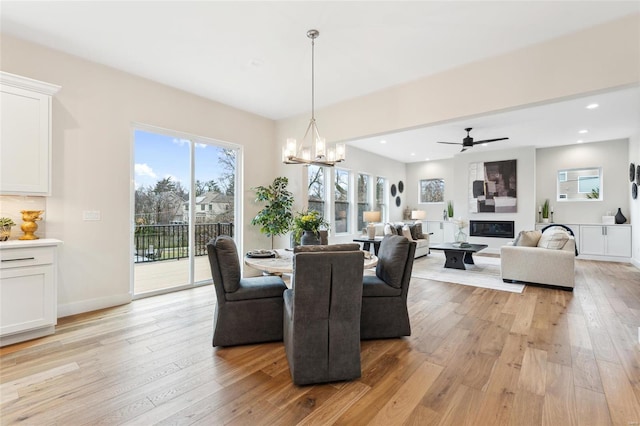 dining space with light wood-style flooring, ceiling fan with notable chandelier, baseboards, and recessed lighting