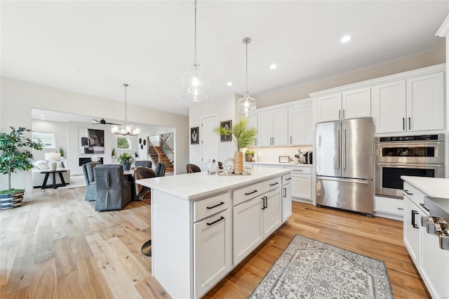 kitchen with light wood-style floors, white cabinetry, light countertops, stainless steel appliances, and backsplash