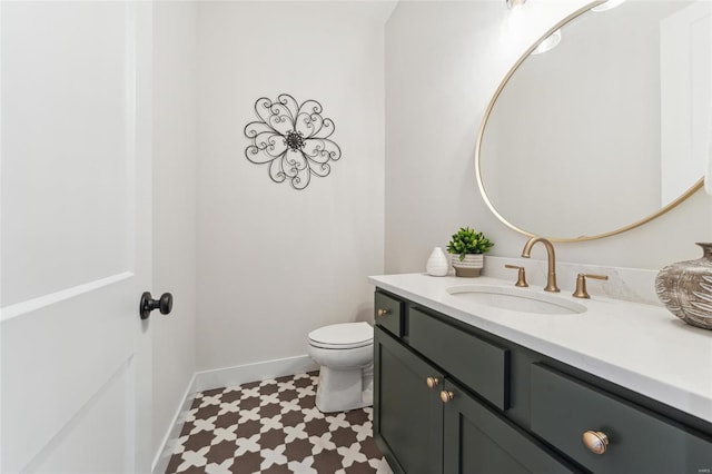 half bath featuring tile patterned floors, toilet, vanity, and baseboards