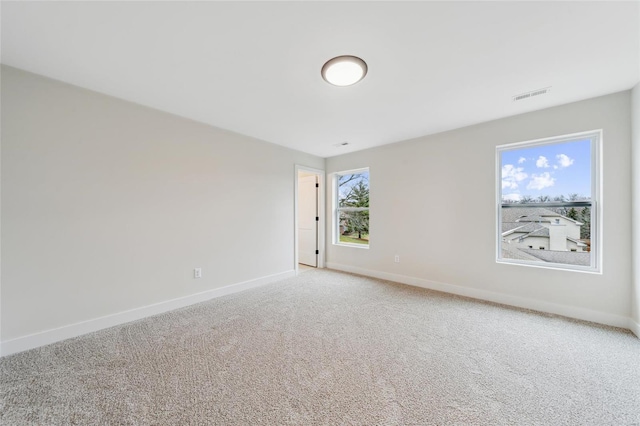 empty room featuring light carpet, baseboards, and visible vents