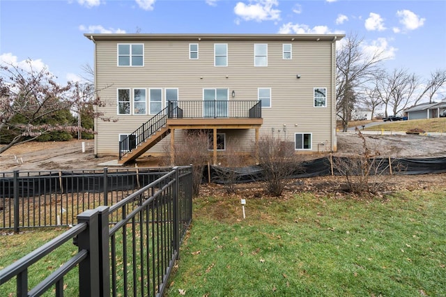 rear view of property featuring a yard, stairway, a deck, and fence