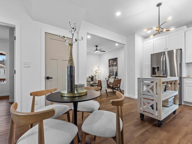 dining room featuring ceiling fan with notable chandelier and dark wood-type flooring