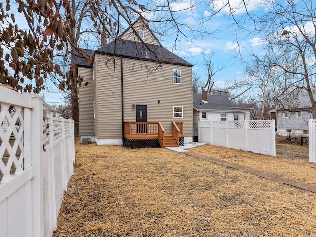 back of property featuring a wooden deck and a yard