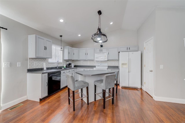 kitchen with lofted ceiling, white appliances, a center island, and decorative backsplash