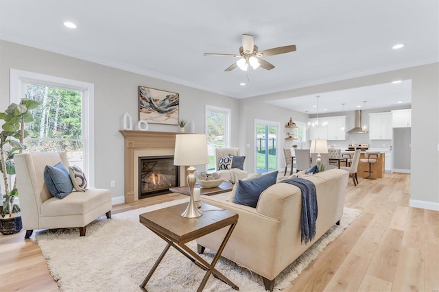 living room featuring ornamental molding, light hardwood / wood-style floors, and ceiling fan