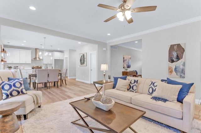 living room with ornamental molding, ceiling fan, and light wood-type flooring