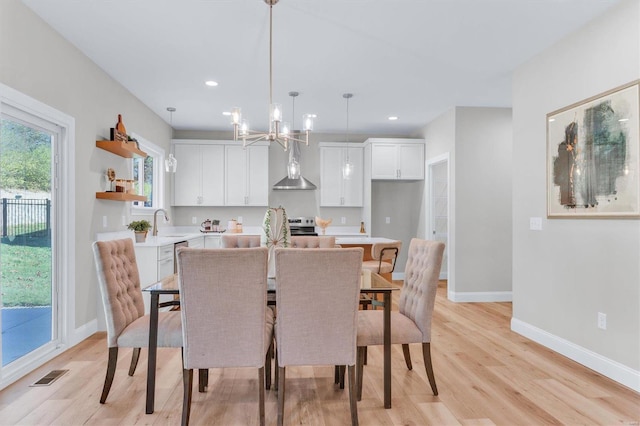 dining space featuring sink, a chandelier, and light hardwood / wood-style floors