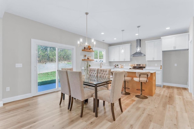 dining space with sink, light hardwood / wood-style flooring, and a notable chandelier