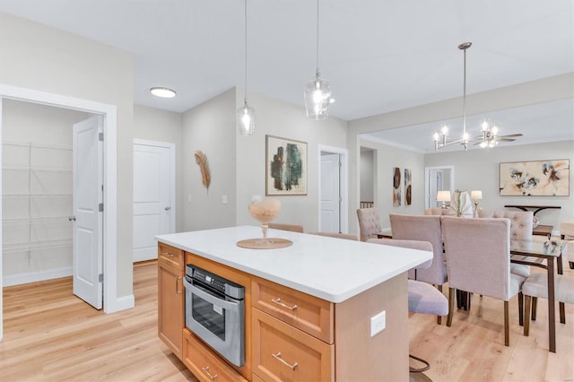 kitchen with pendant lighting, light hardwood / wood-style floors, a kitchen breakfast bar, and a kitchen island