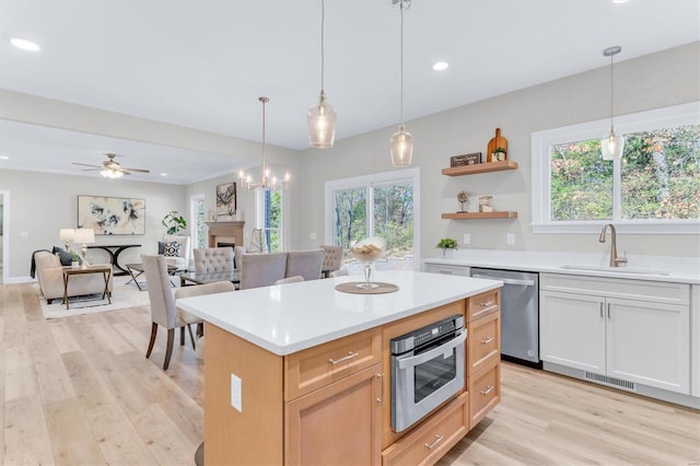 kitchen featuring a kitchen island, white cabinetry, sink, hanging light fixtures, and stainless steel appliances