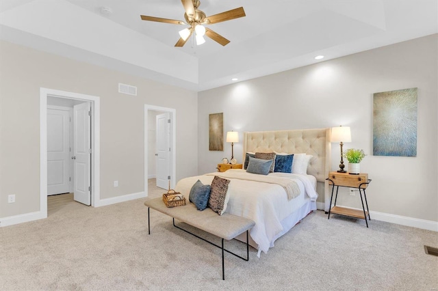 carpeted bedroom featuring ceiling fan and a tray ceiling