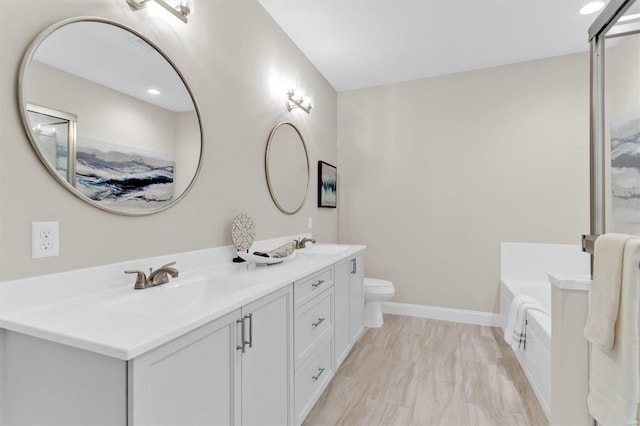 bathroom featuring vanity, a tub to relax in, and toilet