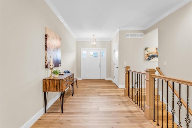 foyer entrance with ornamental molding, a chandelier, and light wood-type flooring