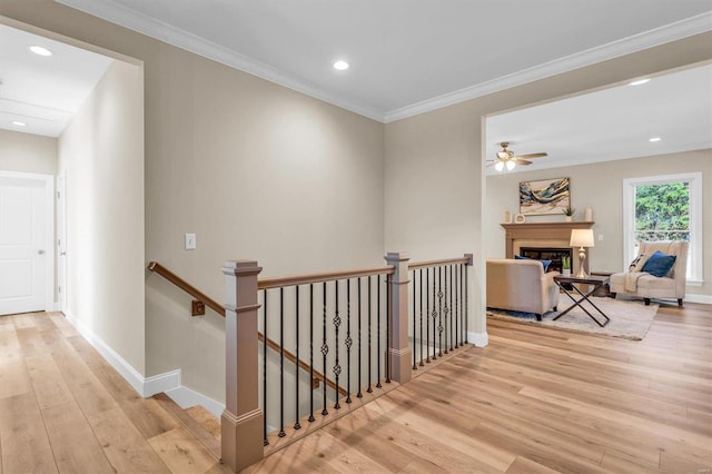 corridor with ornamental molding and light hardwood / wood-style floors