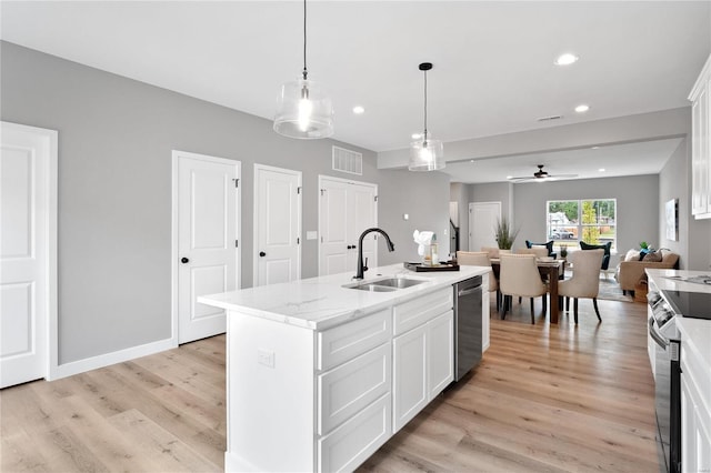 kitchen with decorative light fixtures, white cabinetry, sink, a kitchen island with sink, and stainless steel appliances