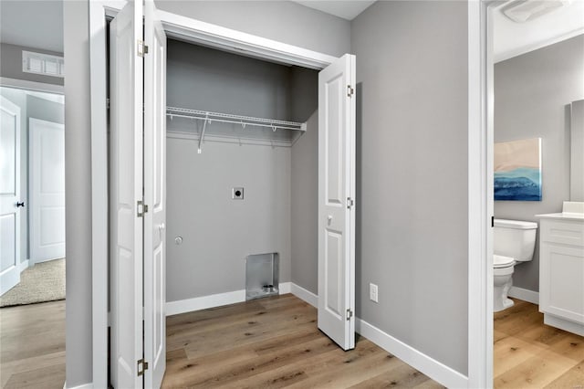 clothes washing area featuring light hardwood / wood-style floors and hookup for an electric dryer