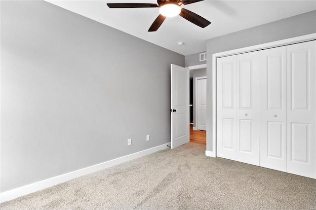 unfurnished bedroom with ceiling fan, a closet, and light carpet