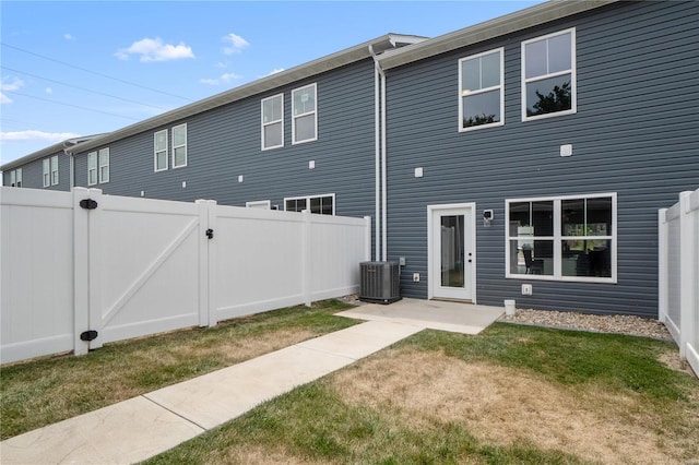 back of house with central AC and a yard