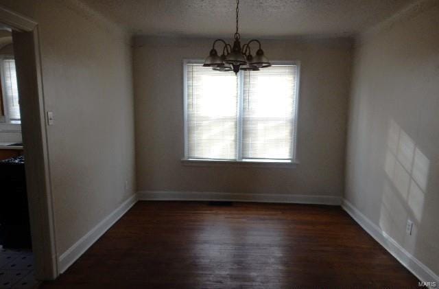 unfurnished dining area with an inviting chandelier, baseboards, dark wood-style flooring, and a textured ceiling