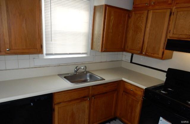 kitchen featuring black appliances, extractor fan, light countertops, and a sink