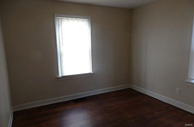 spare room featuring dark wood finished floors and baseboards