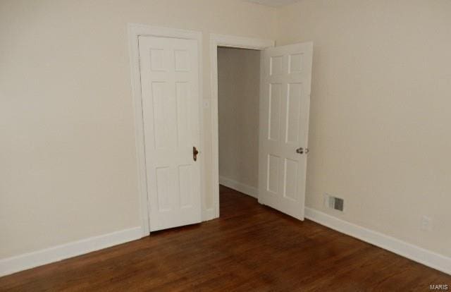 unfurnished bedroom featuring dark wood finished floors, visible vents, and baseboards