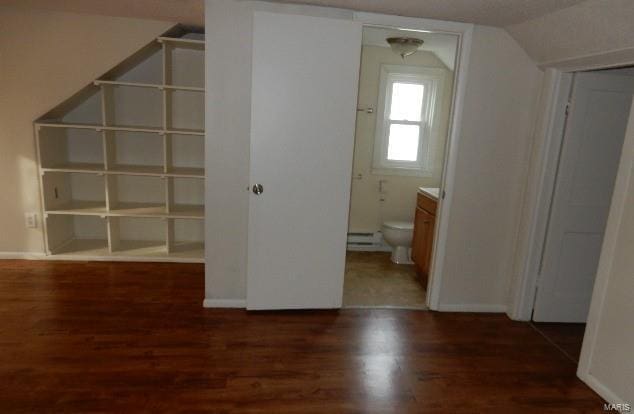 interior space featuring vaulted ceiling, a baseboard radiator, baseboards, and wood finished floors