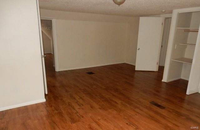 interior space with baseboards, a textured ceiling, and wood finished floors