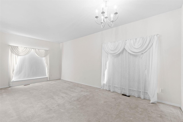 unfurnished room featuring light carpet and a chandelier