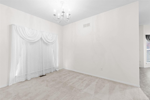 carpeted spare room with a notable chandelier