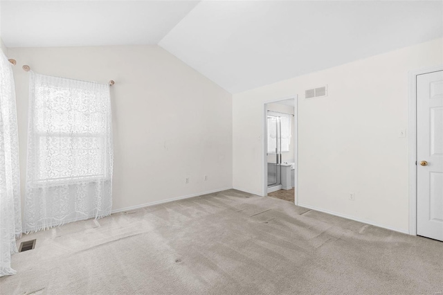 unfurnished room featuring vaulted ceiling and light carpet