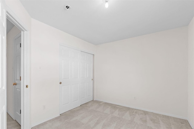 unfurnished bedroom featuring light carpet and a closet