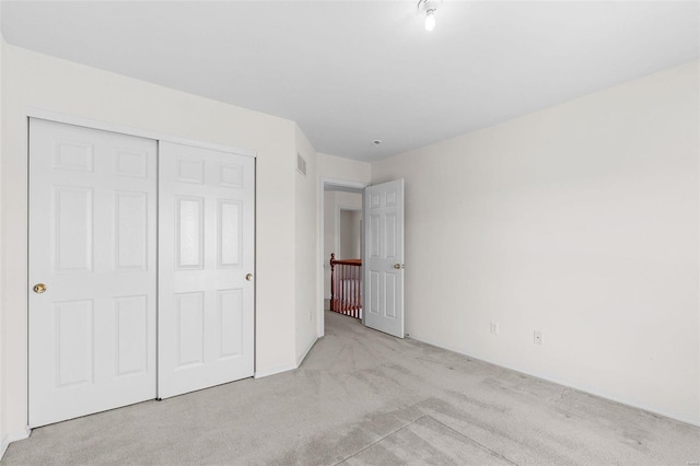 unfurnished bedroom with light carpet and a closet