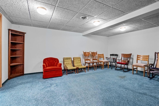 living area with a paneled ceiling and carpet flooring