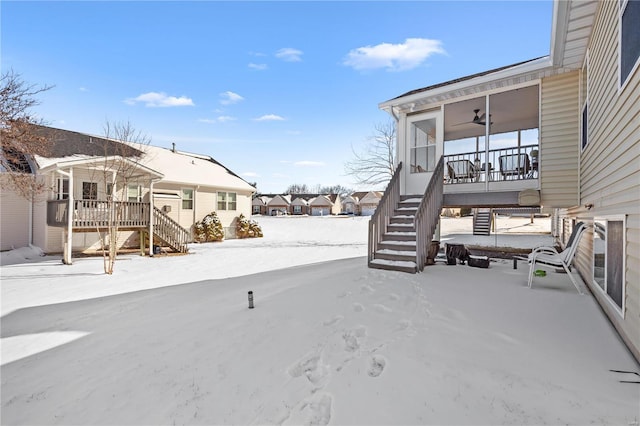 yard covered in snow with a ceiling fan, a porch, and stairs