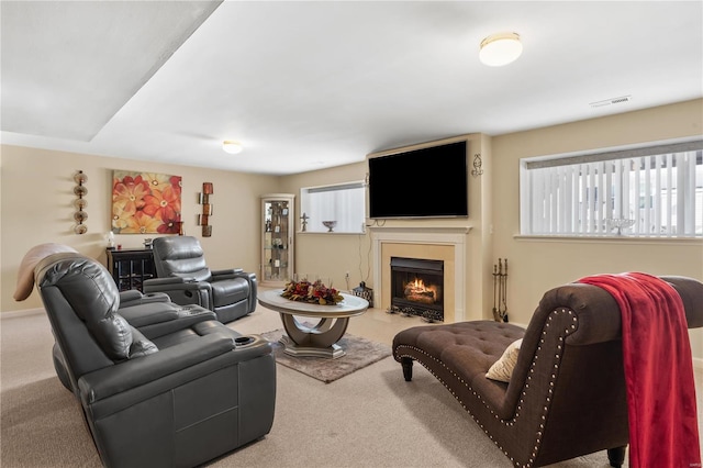 carpeted living room featuring a lit fireplace and visible vents