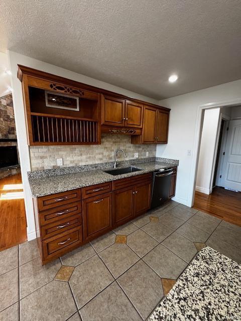 kitchen featuring sink, dishwasher, light stone countertops, a textured ceiling, and light tile patterned flooring