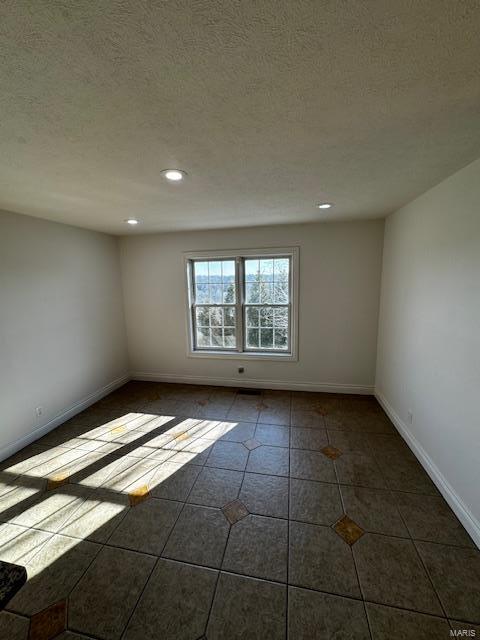 tiled empty room with a textured ceiling