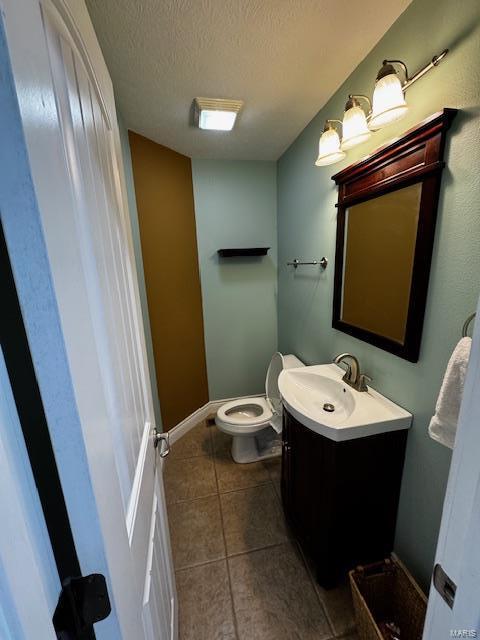 bathroom featuring vanity, toilet, tile patterned flooring, and a textured ceiling